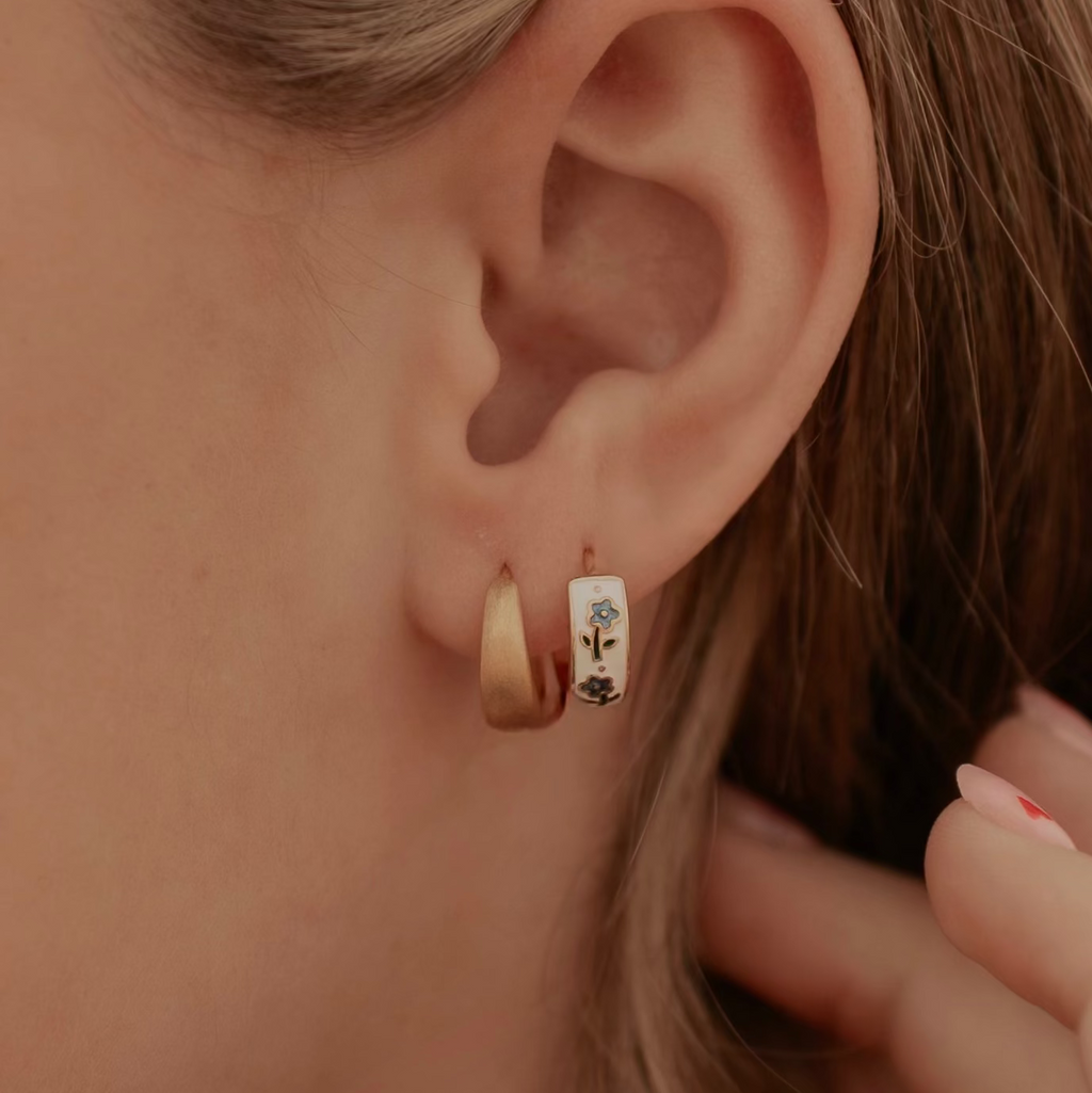 Close-up of an ear wearing gold hoop earrings with a blurred background