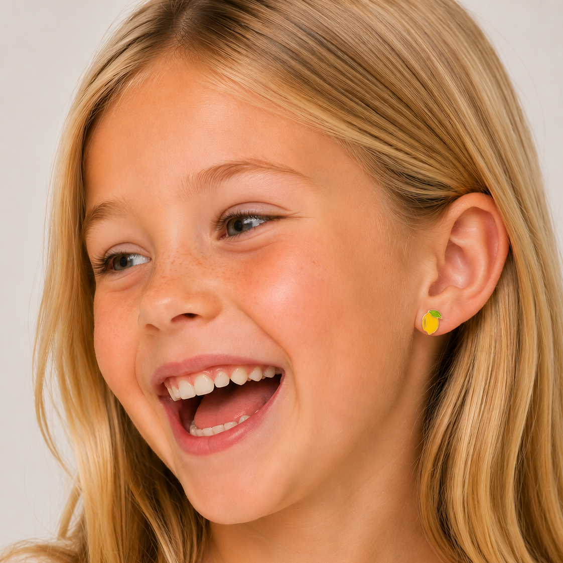 Close-up of a young girl with blonde hair and a white shirt, wearing a yellow earring.