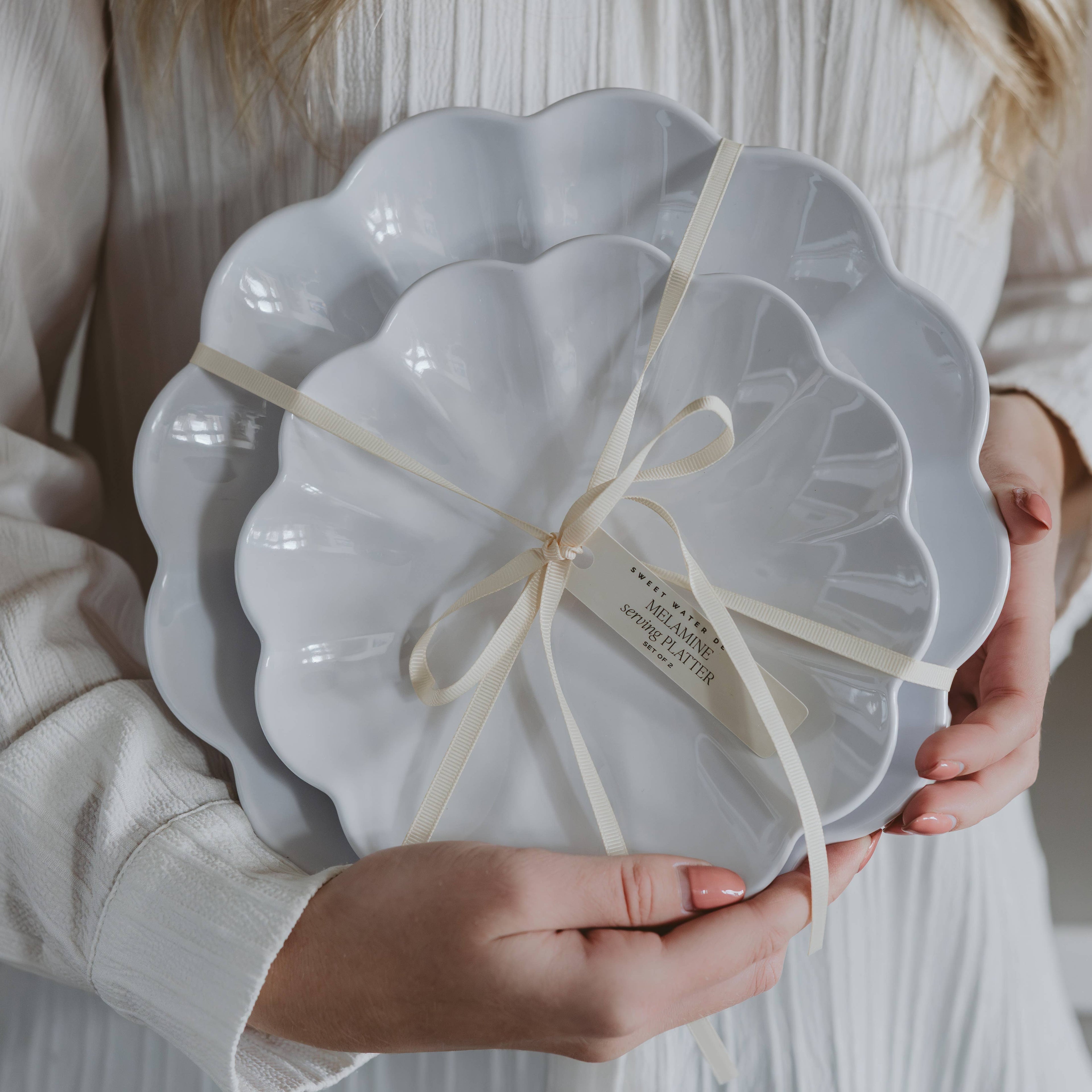 Person holding a white scalloped-edge dish with a bow