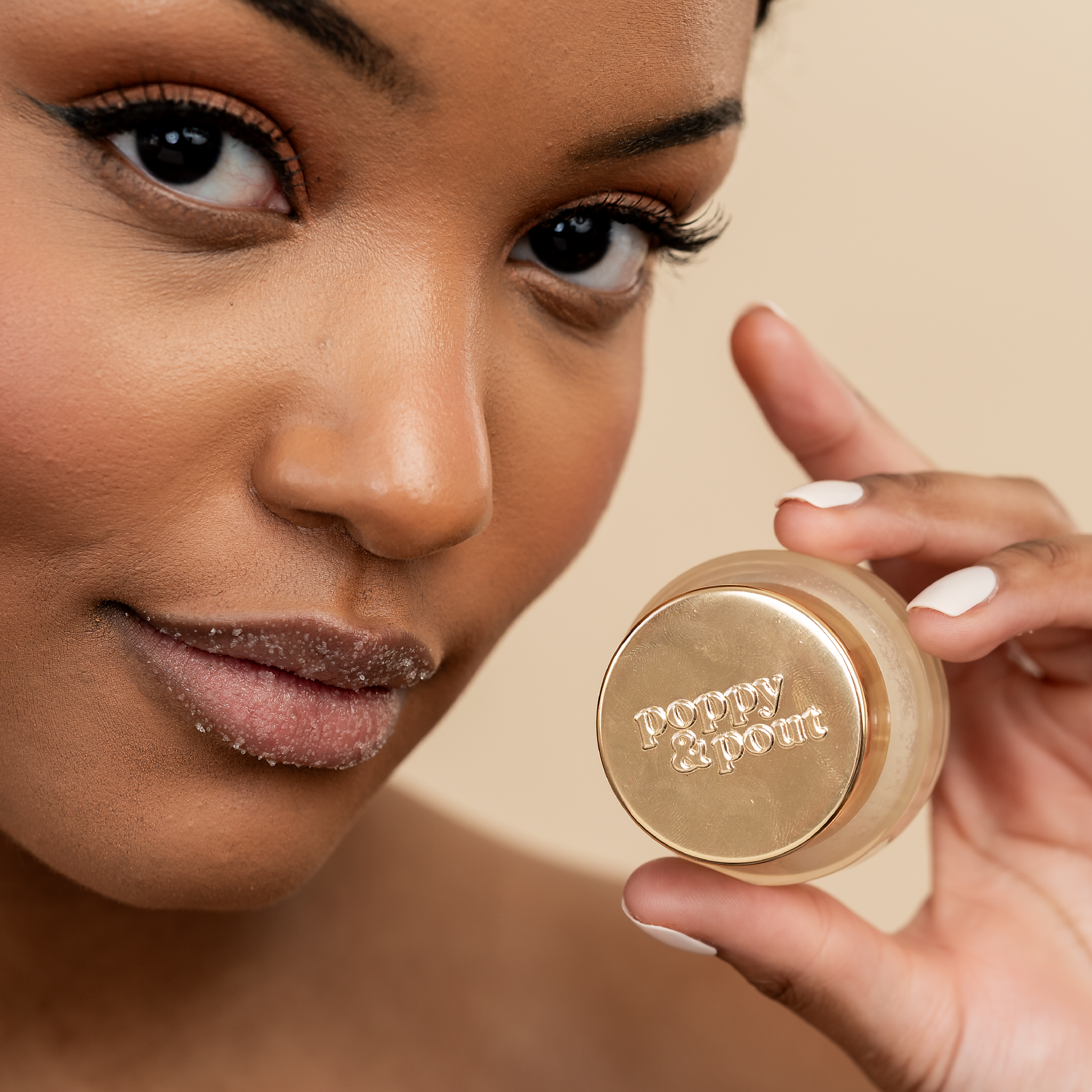 Woman holding a gold compact mirror with 'Poppy & Post' branding.
