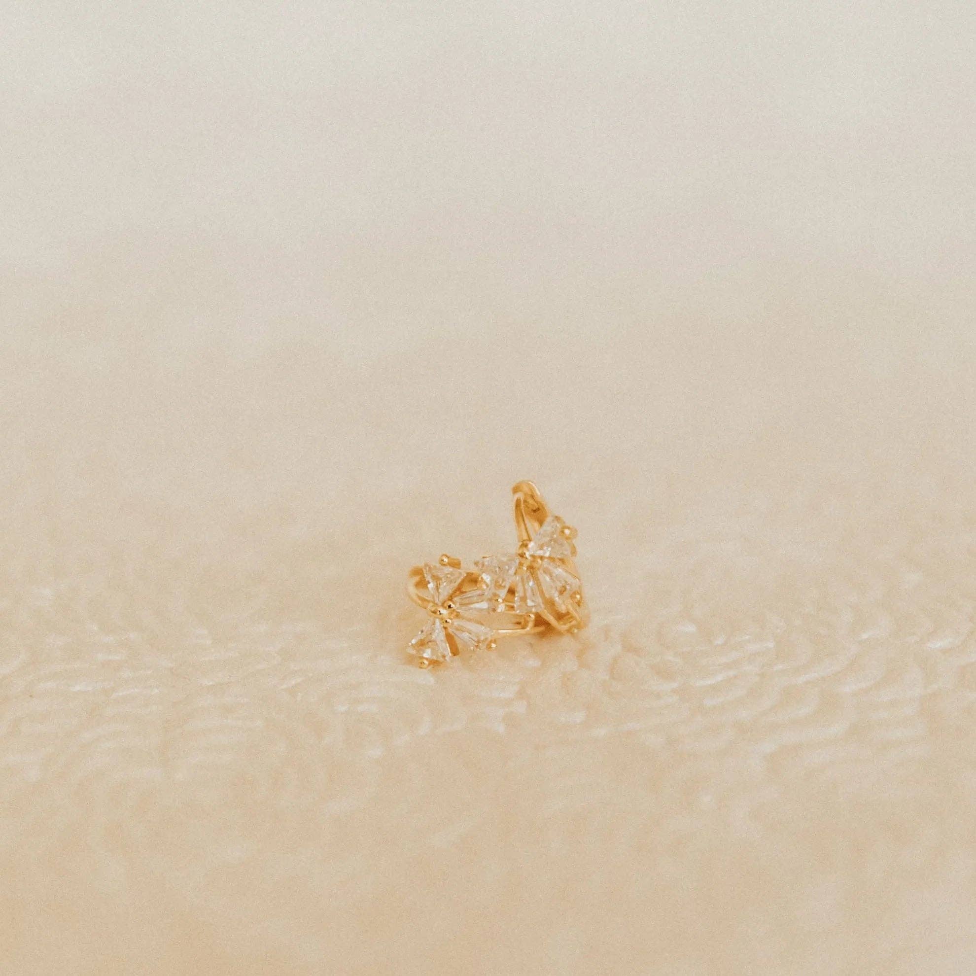 Gold ring with a star design on a beige background
