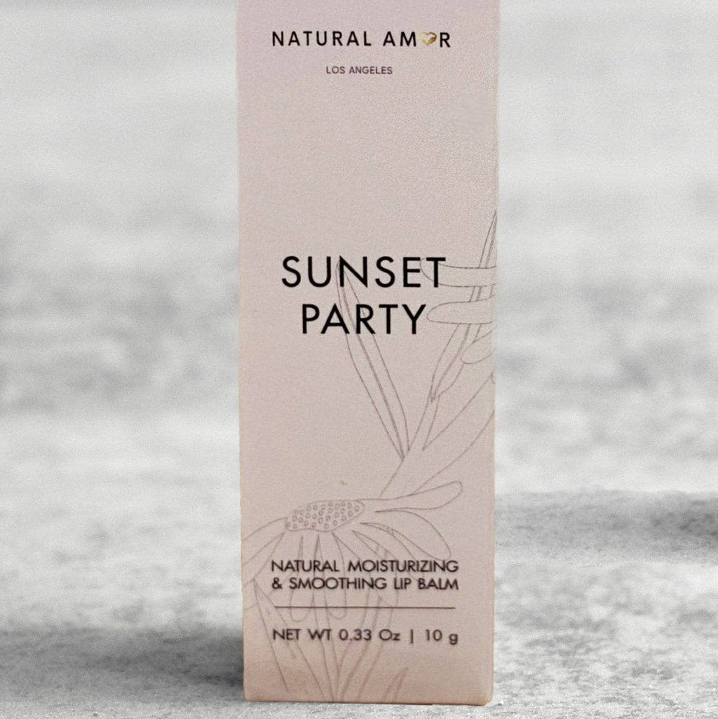 Lip balm and packaging labeled 'Sunset Party' on a light surface with dried flowers.