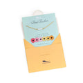 Necklace with a card labeled 'Best Teacher' on a white background