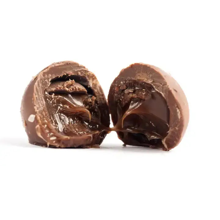 Close-up of a chocolate truffle split in half on a white background