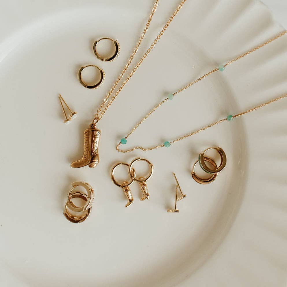 Gold jewelry set including necklaces and rings on a white plate