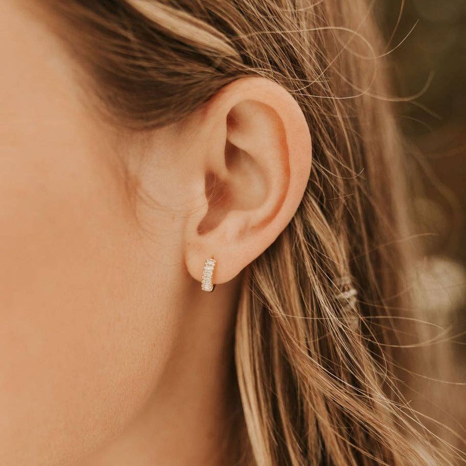 Close-up of an ear wearing a diamond earring with blurred background