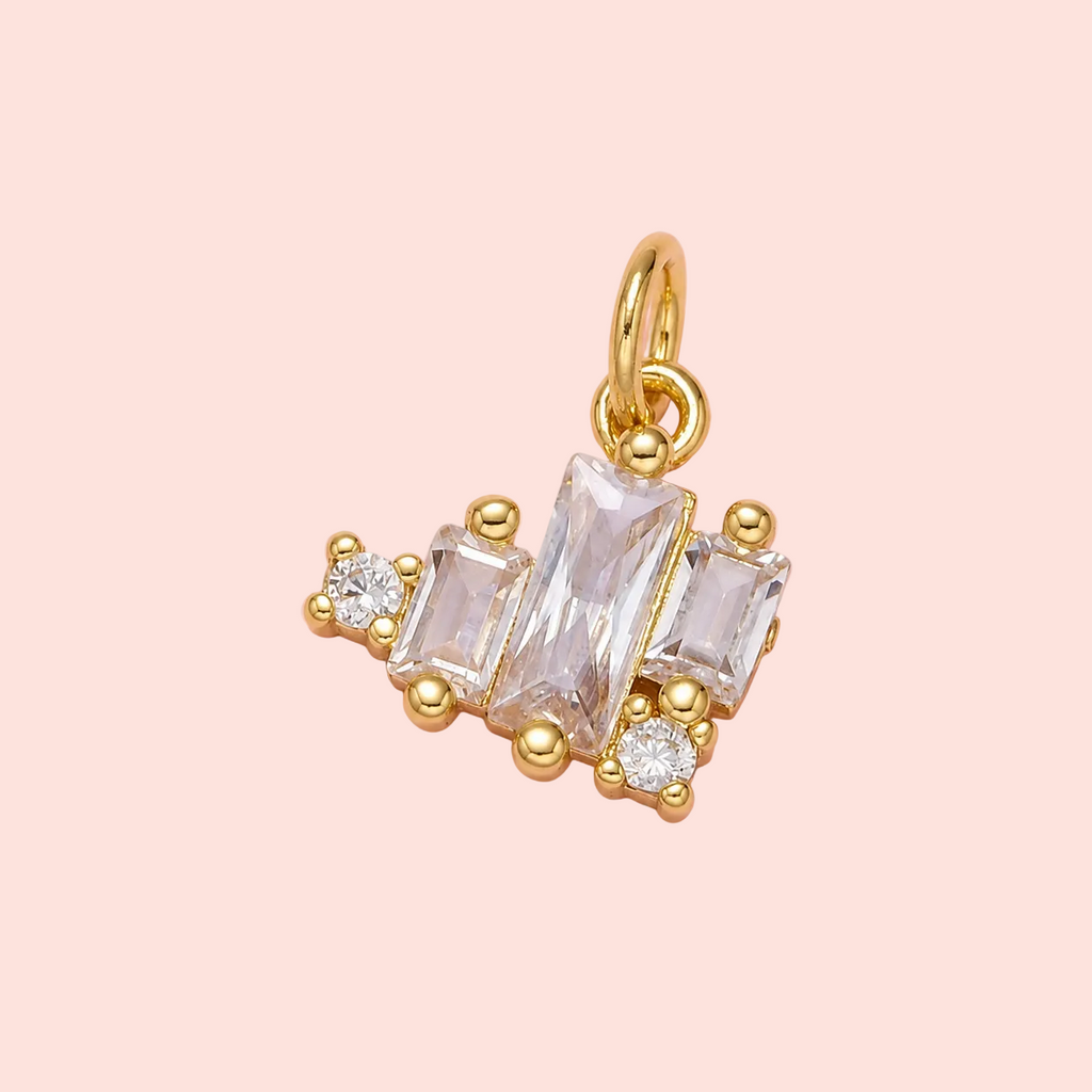 Gold pendant with clear gemstones on a pink background