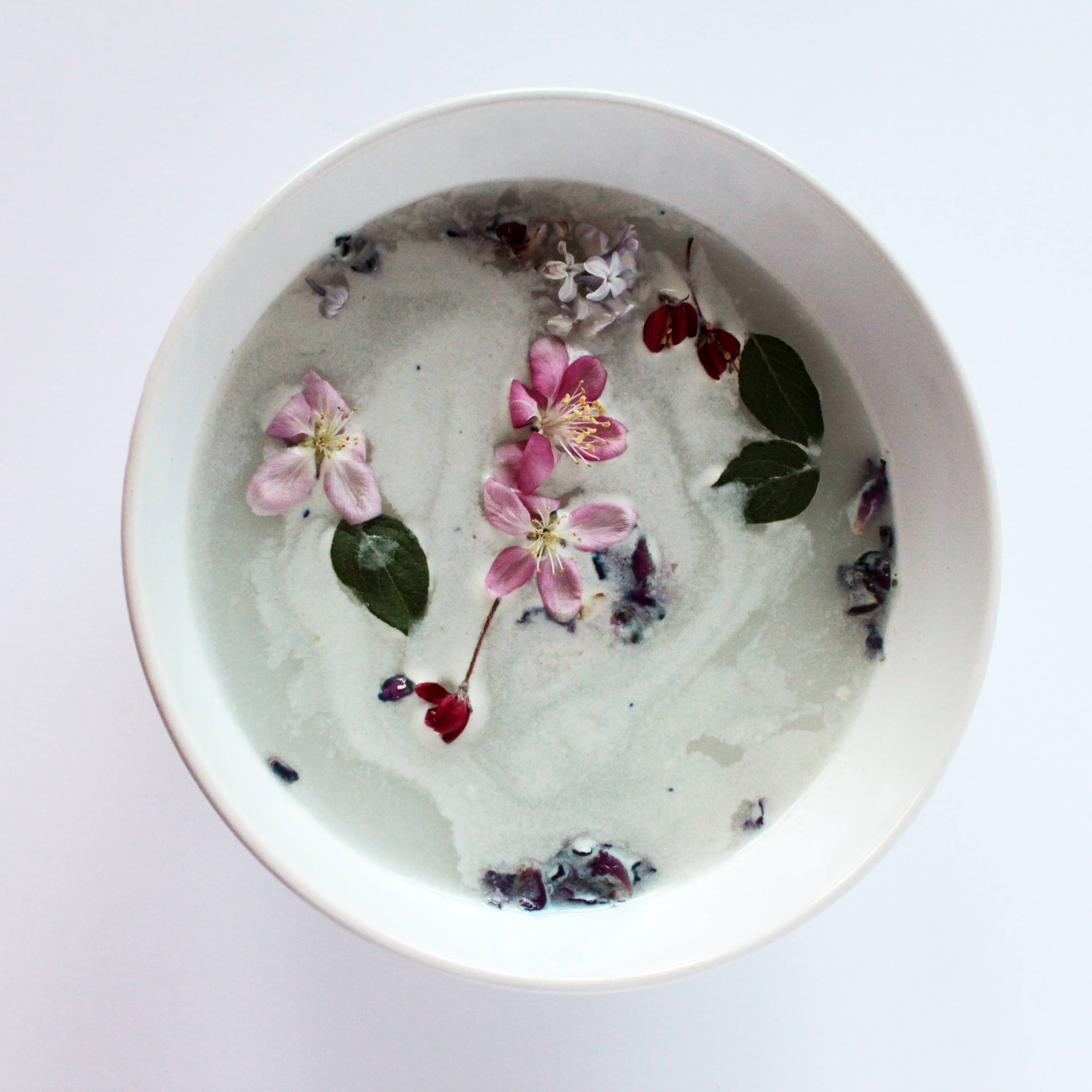 White bowl with floral and leaf arrangement on a white background