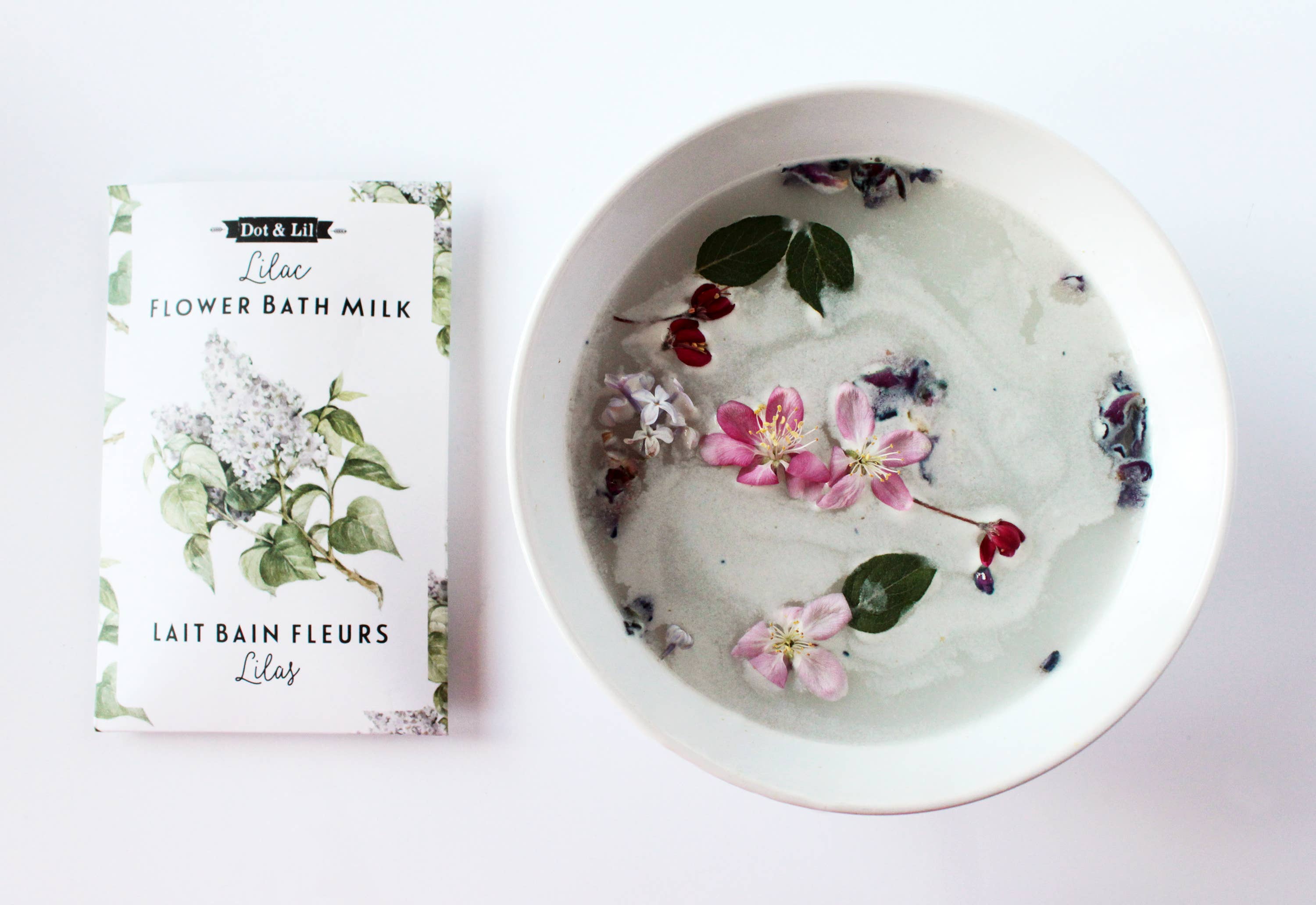 Flower bath milk packaging with a bowl of water and floating flowers on a white background