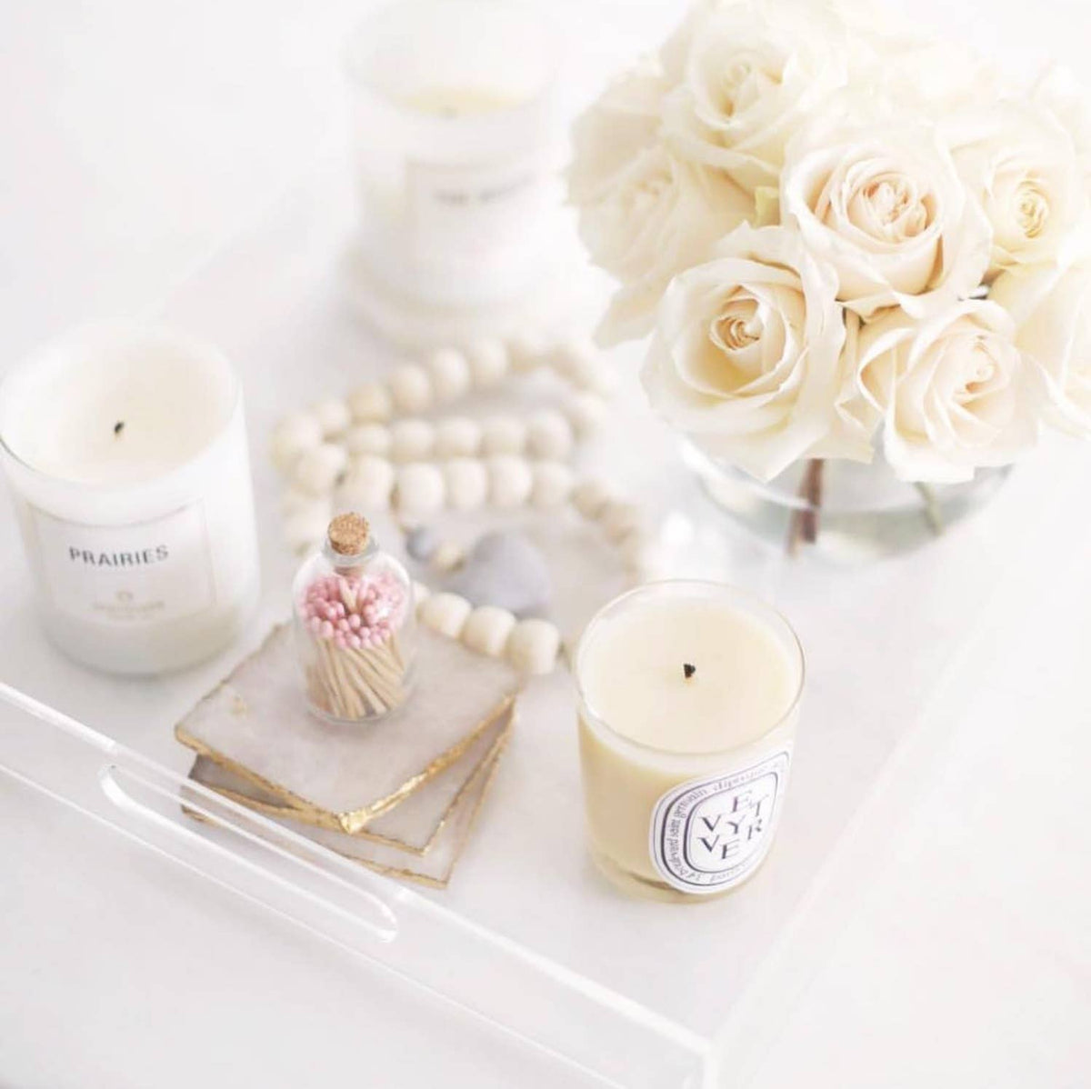 Two candles and a bouquet of white roses on a marble surface