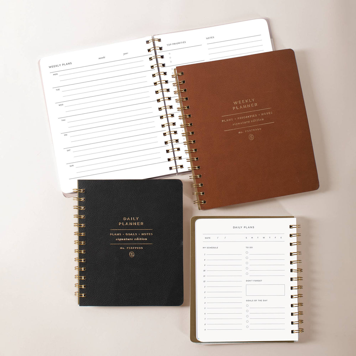 Signature Edition planner collection featuring black daily, brown weekly, and taupe daily planners with gold spiral binding, faux leather covers, and thoughtfully designed planning pages for organizing schedules, goals, notes, and everyday life.