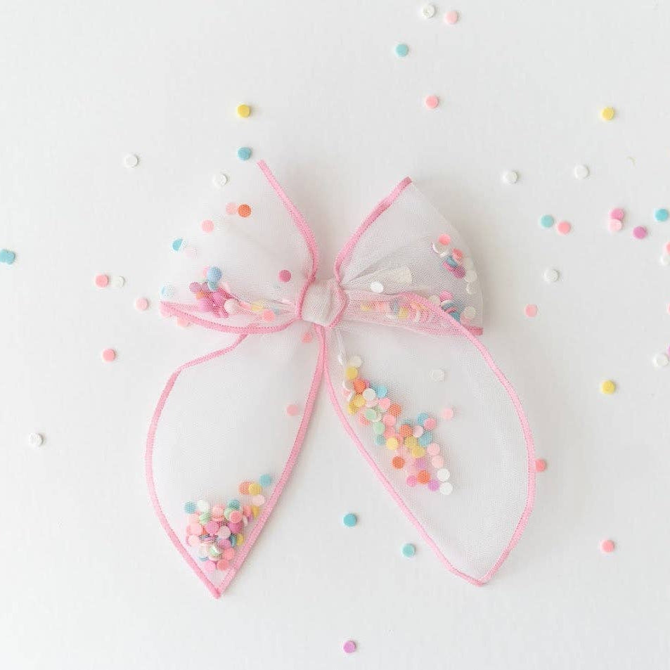 Pink bow with colorful sprinkles on a light background
