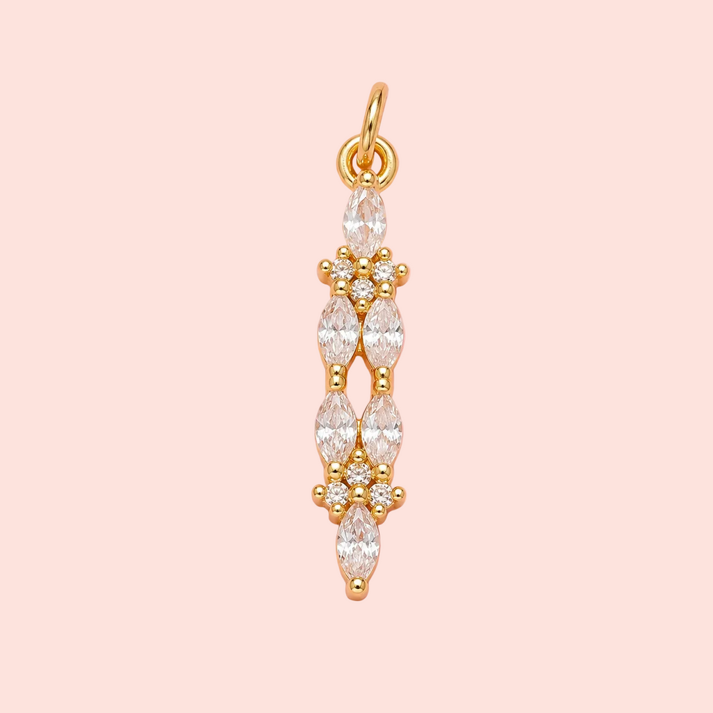Gold pendant with clear stones on a pink background