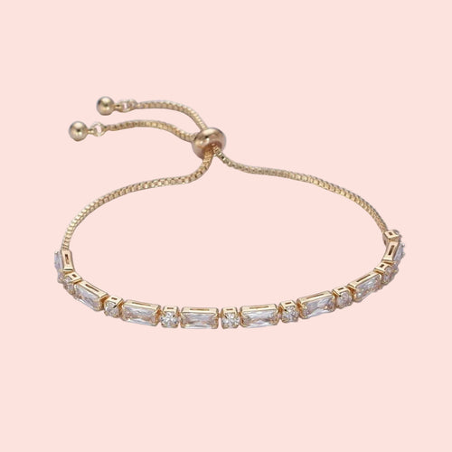 Gold bracelet with clear stones on a light gray background