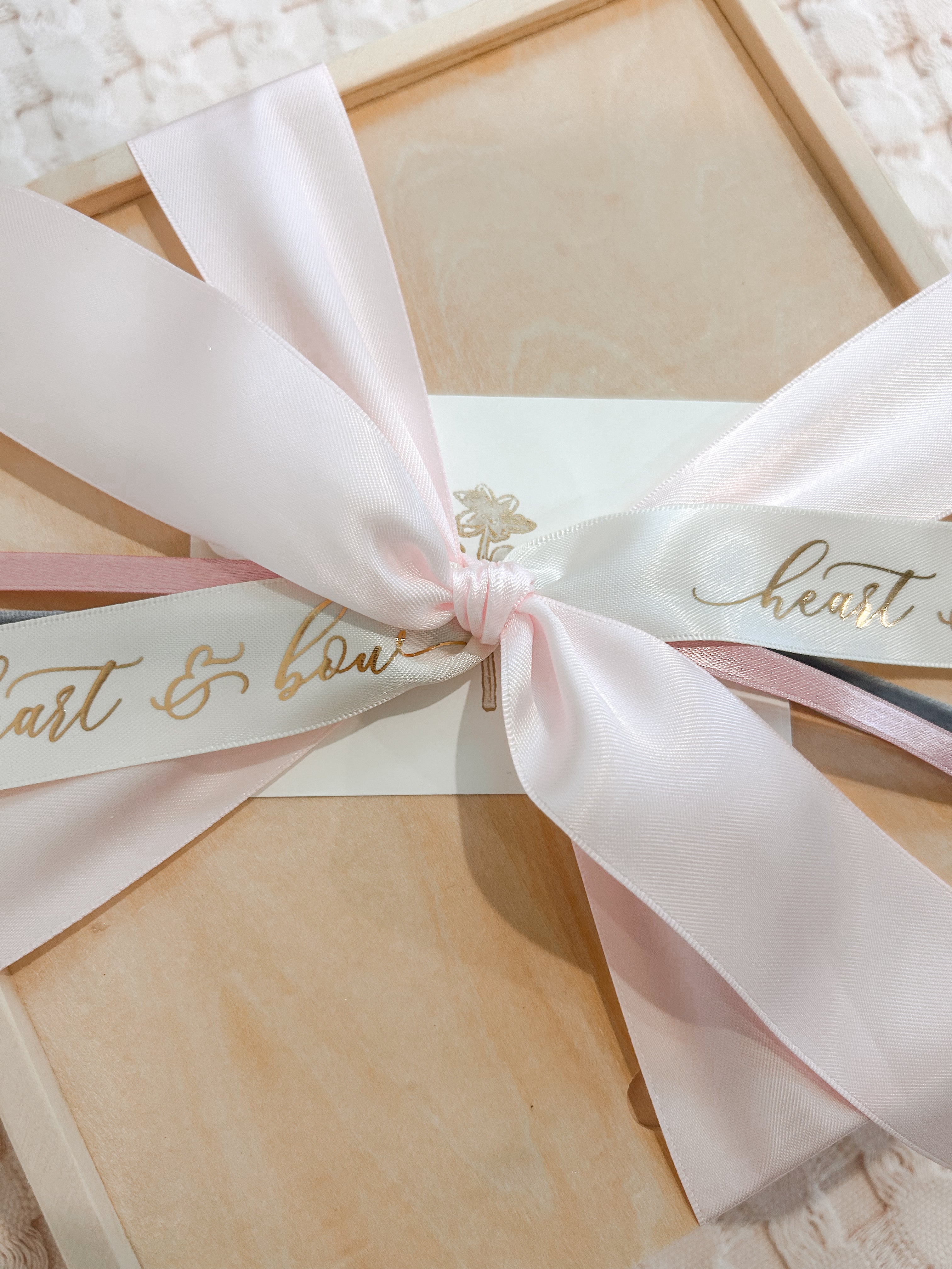 Gift box with a pink ribbon and 'heart & bow' text on a textured surface