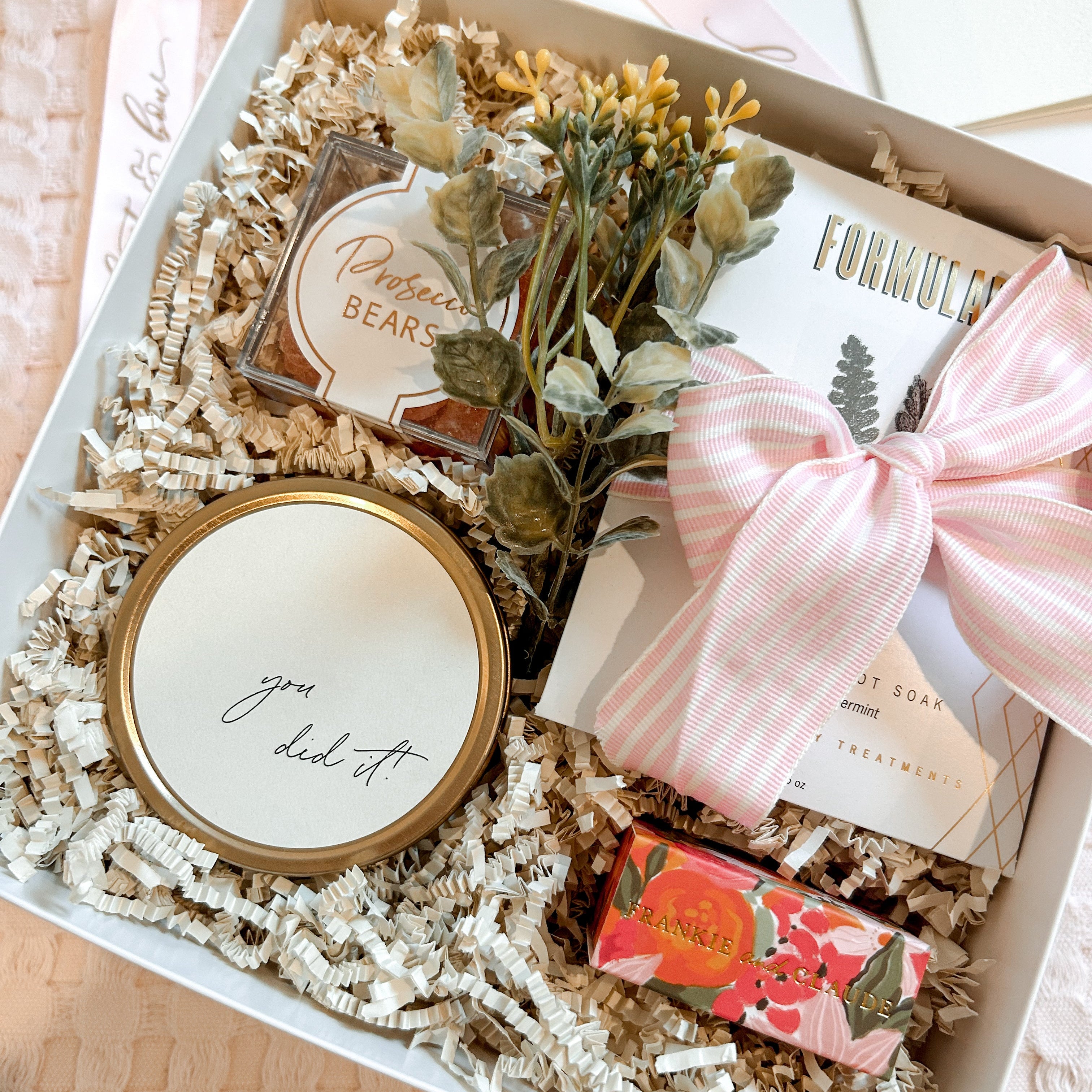 Gift box with a candle, plant, and other items on a wooden surface