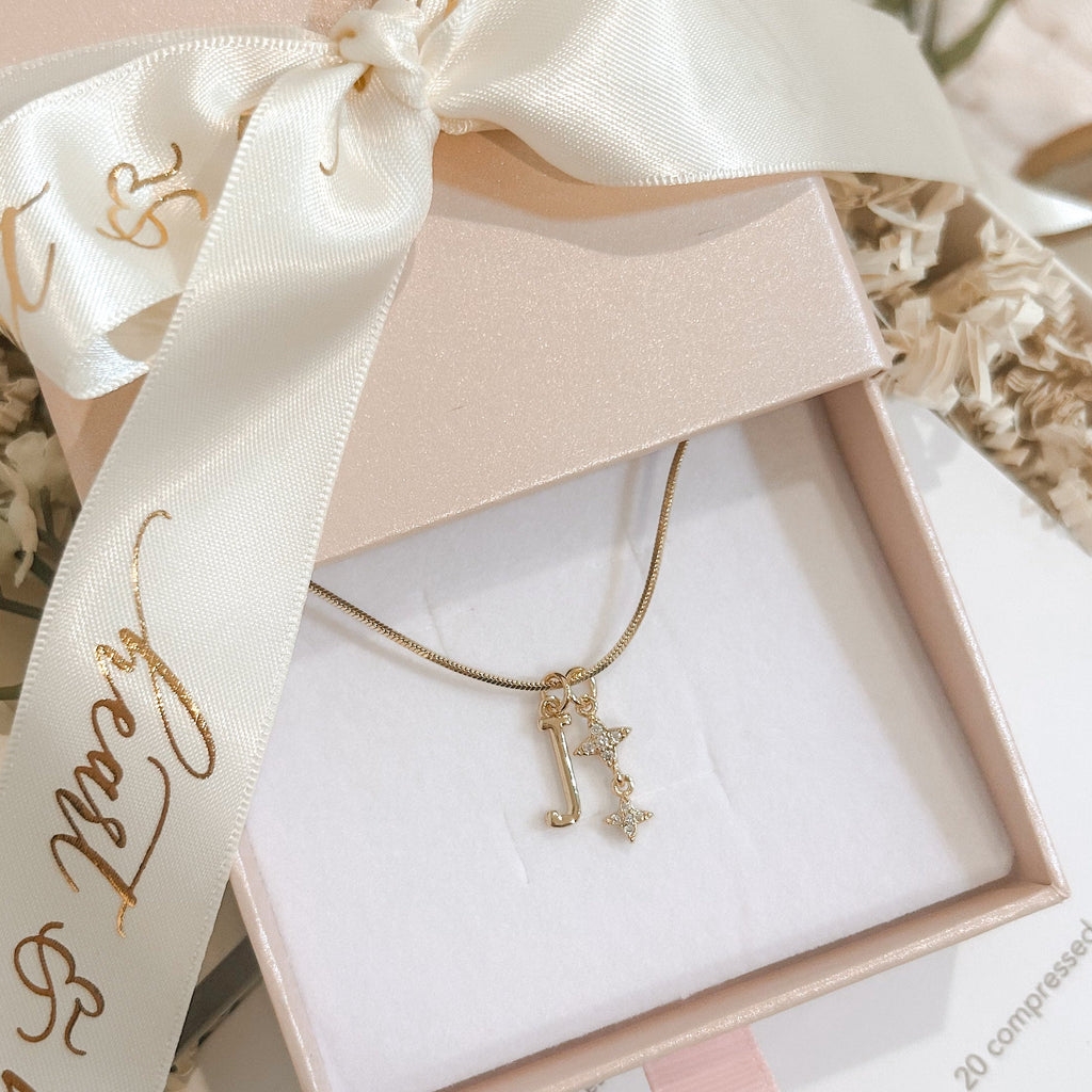 Jewelry box with a gold necklace and decorative ribbon on a soft surface.