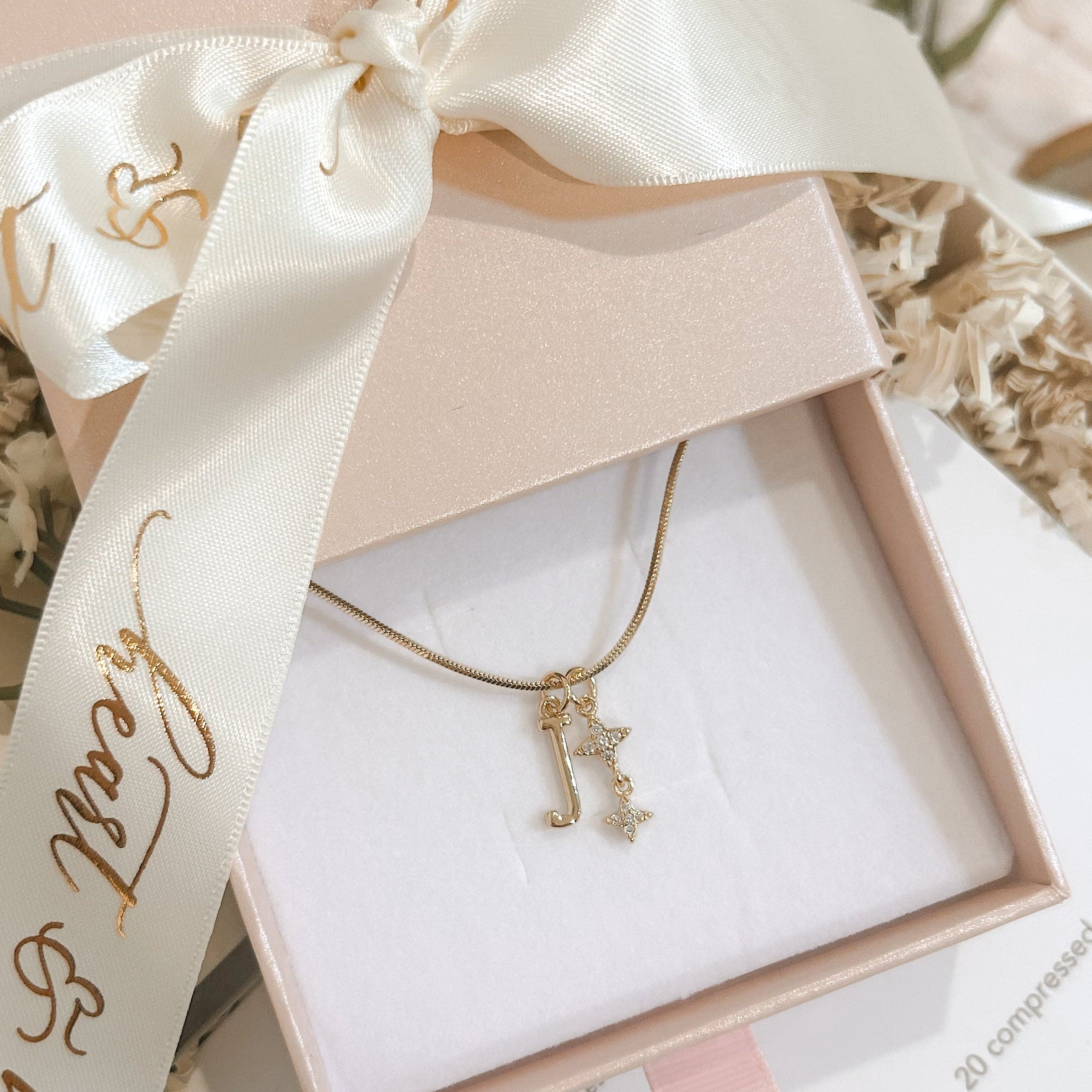 Jewelry box with a gold necklace and decorative ribbon on a soft surface.