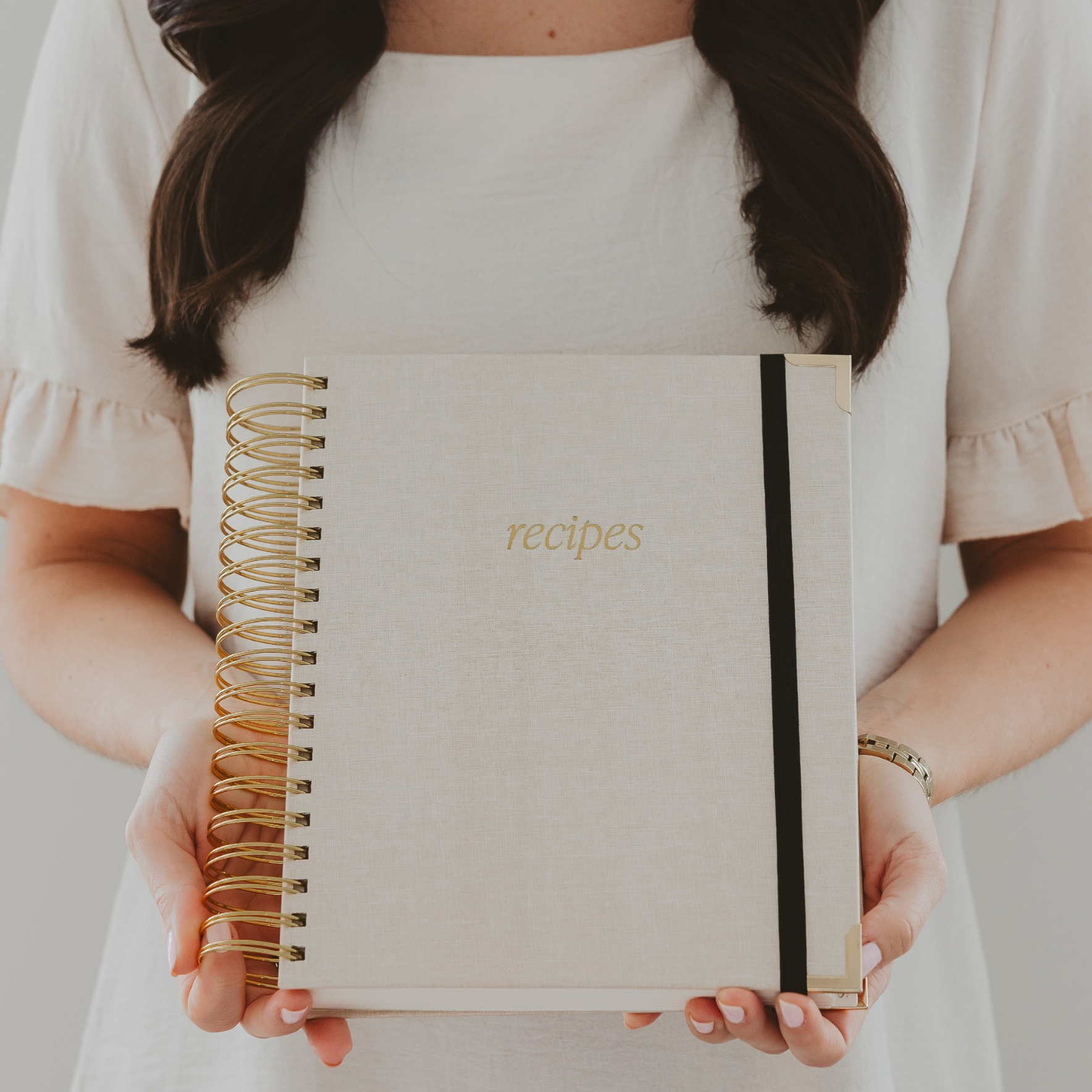 Person holding a recipe notebook with a plain background