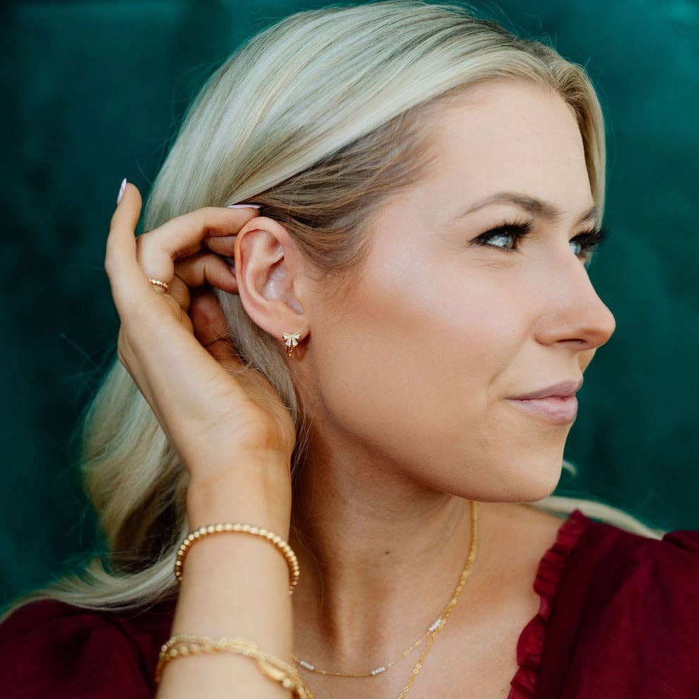 Woman adjusting an earring with a blurred green background