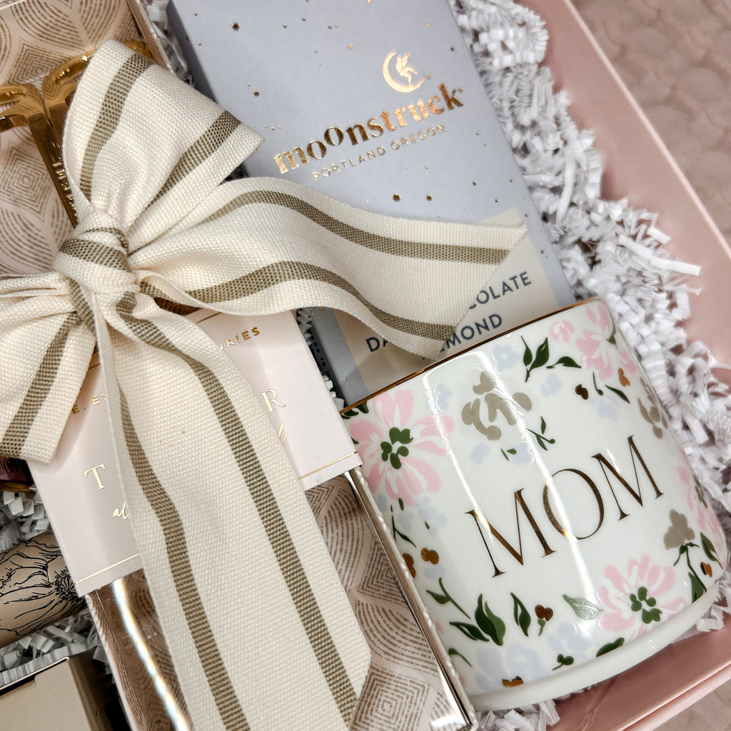 Gift set with a mug, chocolate bar, and bow on a pink surface