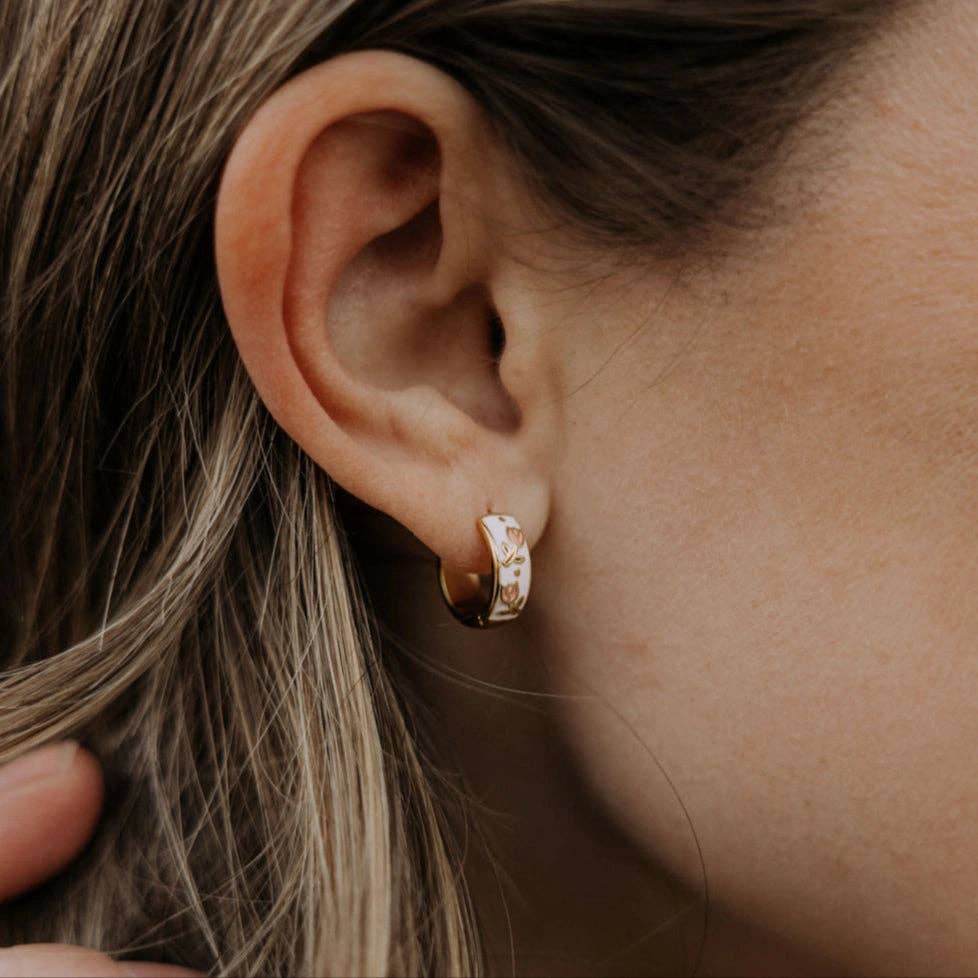 Close-up of an ear wearing a gold hoop earring with a blurred background