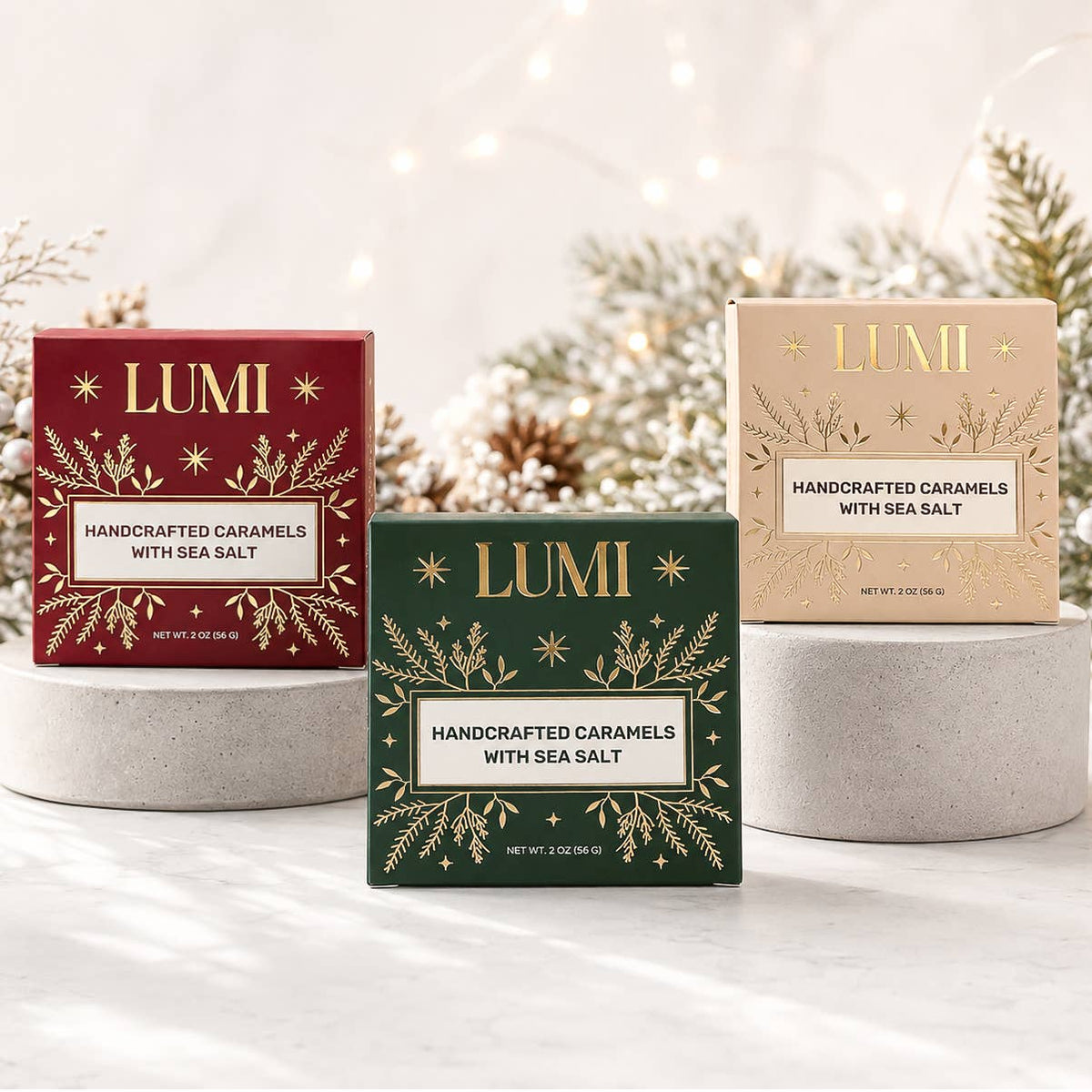 Three LUMI handcrafted caramel boxes with sea salt are displayed on pedestals. The center box is dark green, and the side boxes are deep red and light beige, all decorated with gold leaf patterns and featuring white labels.