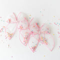 Pink hair bows with colorful sprinkles on a light background