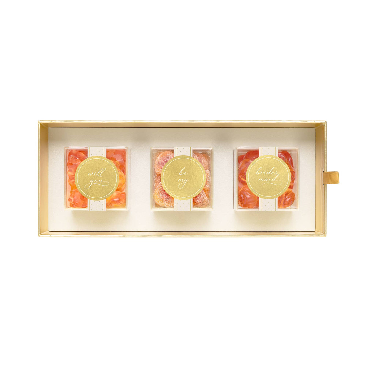A rectangular gift box containing three small clear jars filled with orange-red candies, each topped with a round gold foil seal with elegant script text, set against a plain white background.