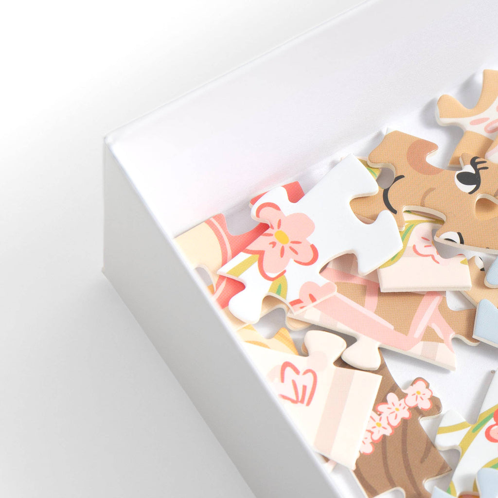 Close-up of colorful jigsaw puzzle pieces inside a white box on a clean white background.