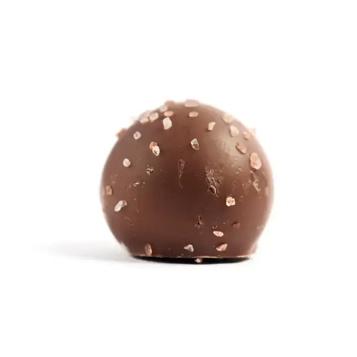 Chocolate truffle with rose gold sprinkles on a white background