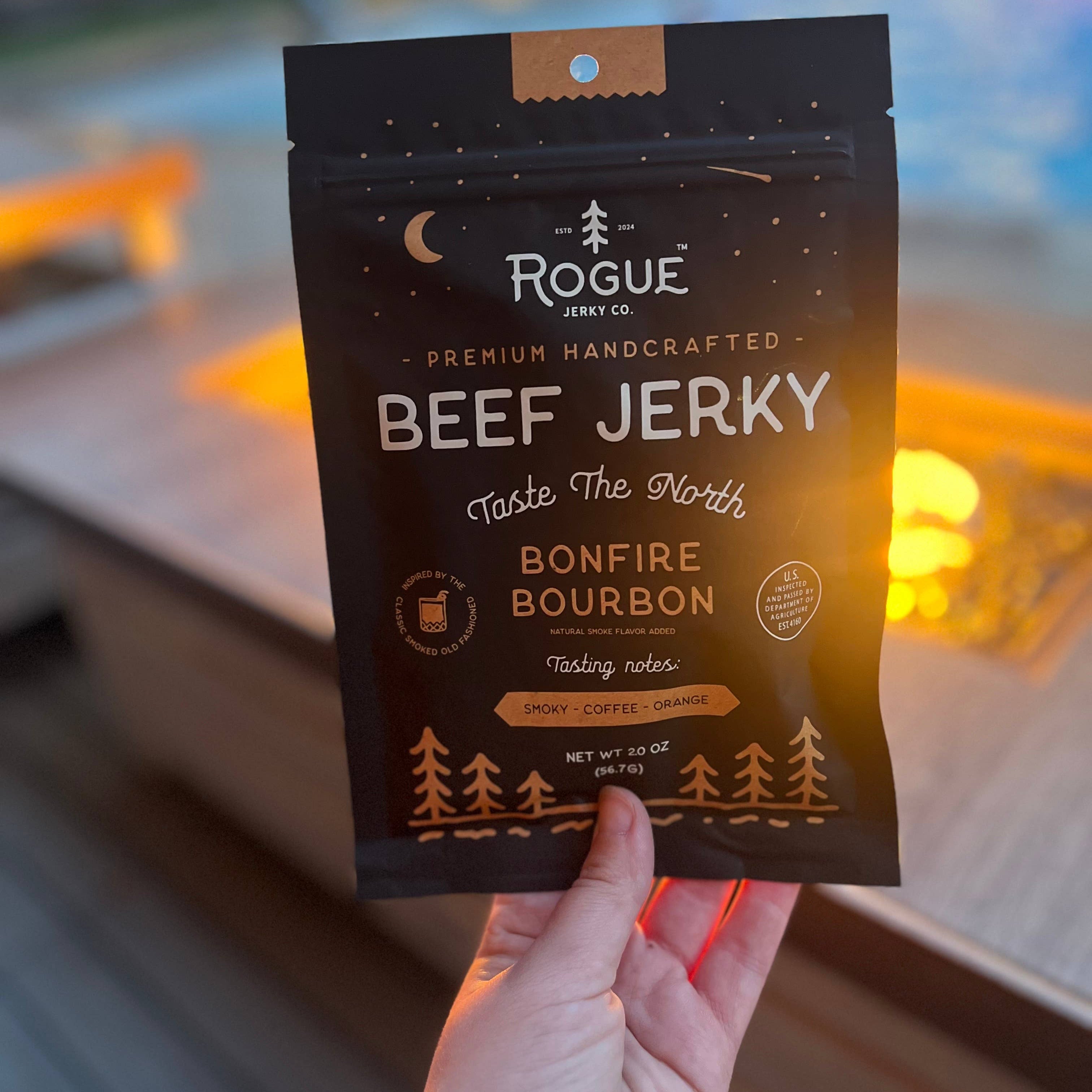 Hand holding a package of Rogue Beef Jerky with a blurred background