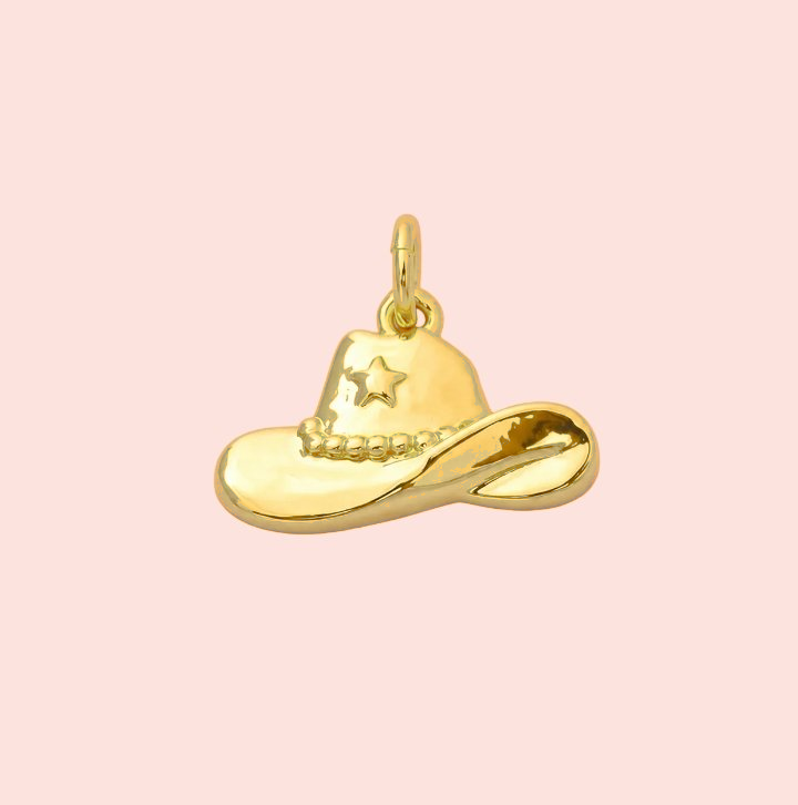 Gold cowboy hat charm on a pink background