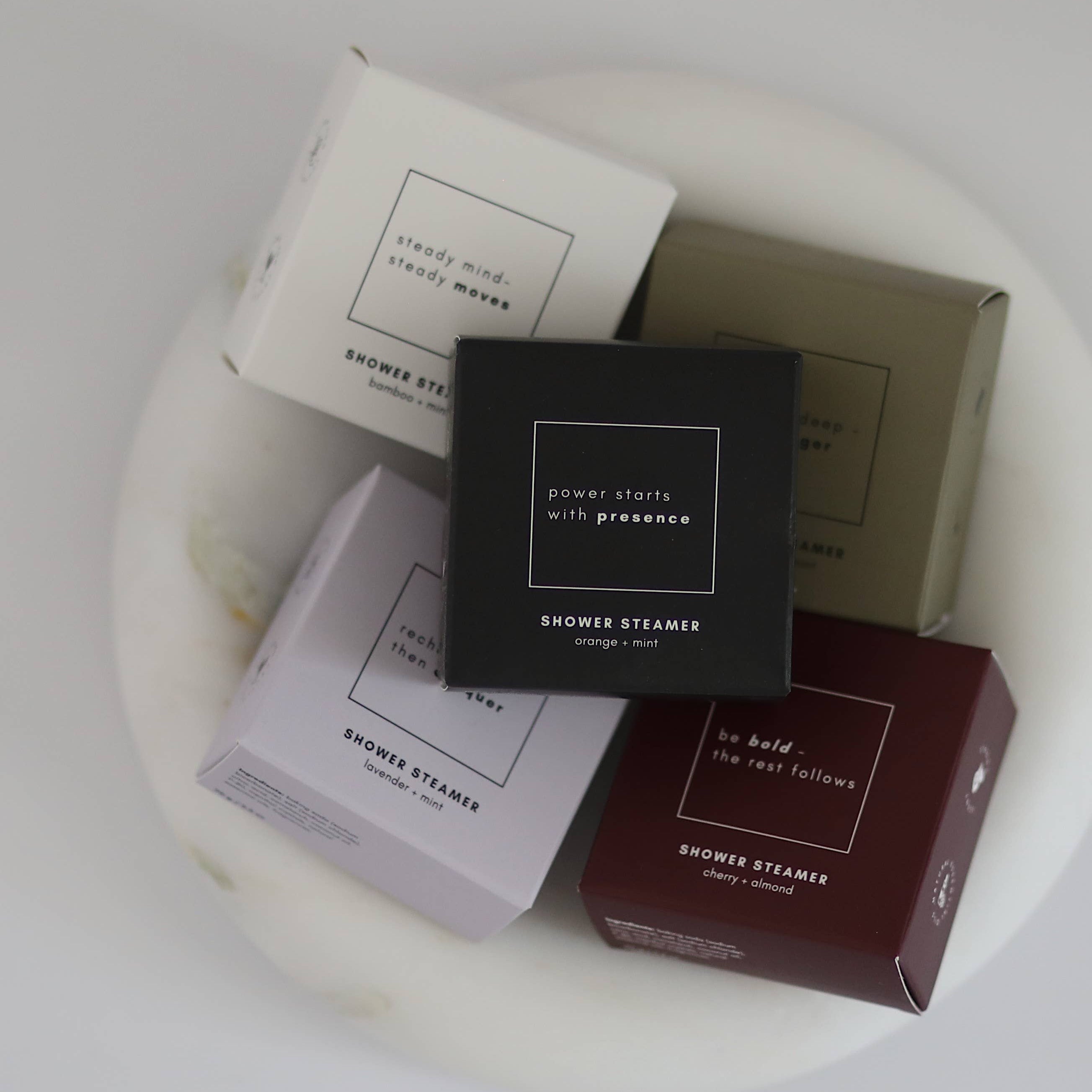 Collection of shower steamers in various packaging on a white surface