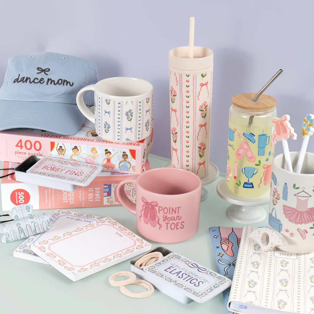 Collection of dance-themed products including mugs, a tumbler, and stationery on a light blue surface with a purple background.