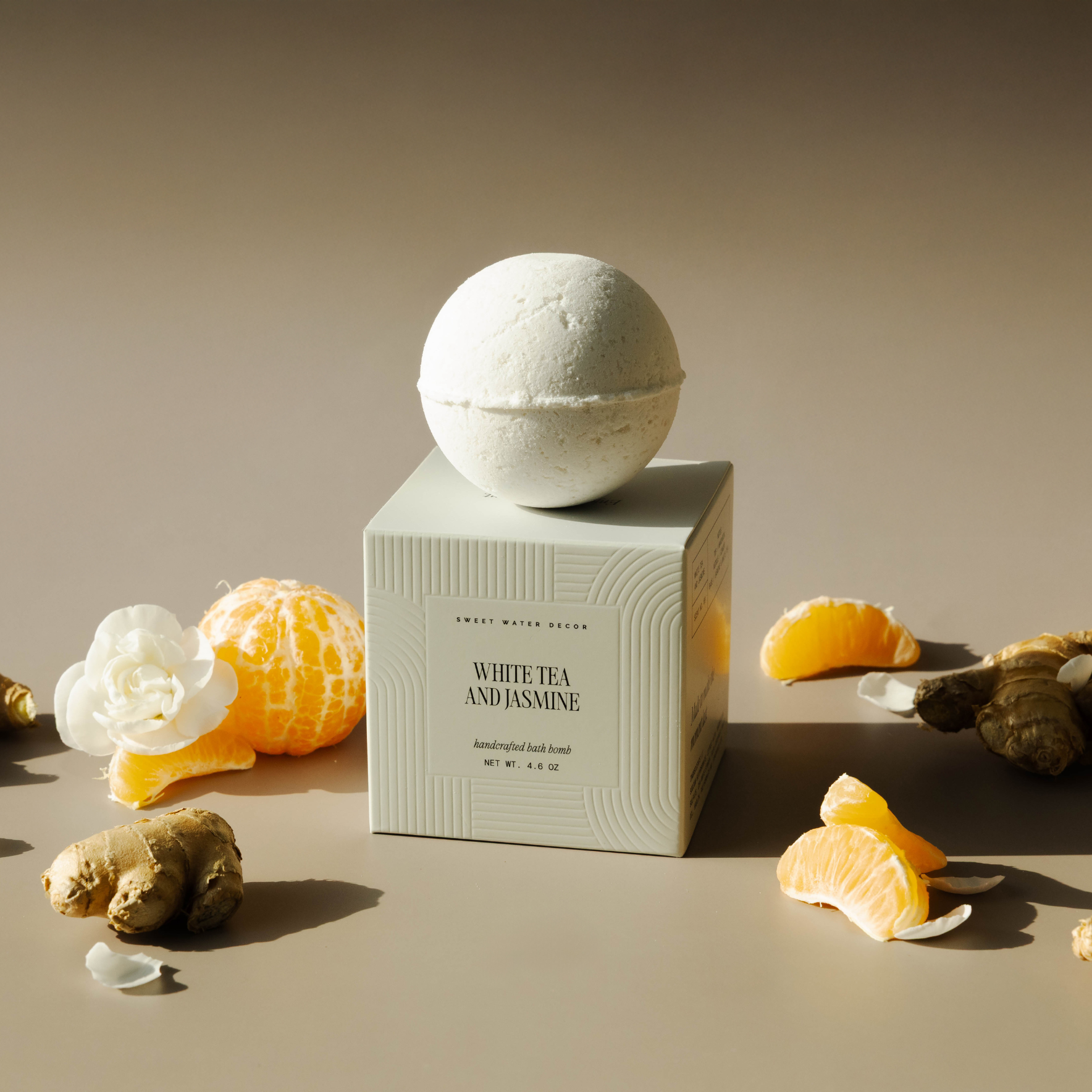 Bath bomb with packaging on a beige surface with oranges and flowers
