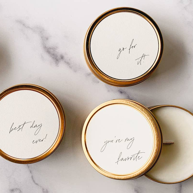 Set of gold and white containers with text on lids on a marble surface