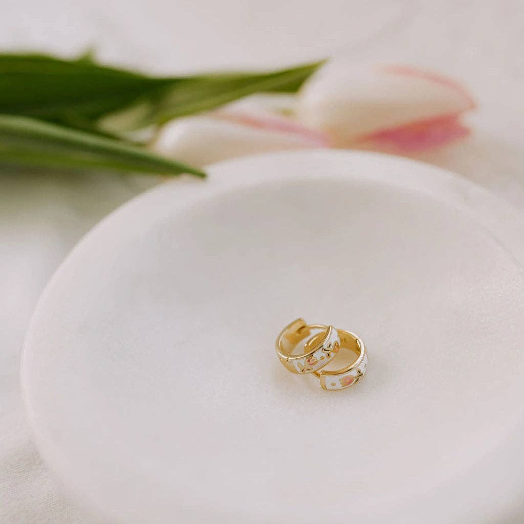 Gold ring on a white dish with tulips in the background
