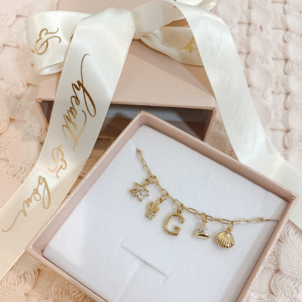 Gold necklace with charms in a box with a decorative ribbon