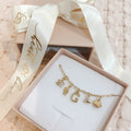 Gold necklace with charms in a box with a decorative ribbon