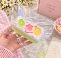 Fruit Cotton Candy Biscuit TABA Squishy featuring a pastel biscuit-inspired design with colorful fruit decorations, individually wrapped in clear packaging.
