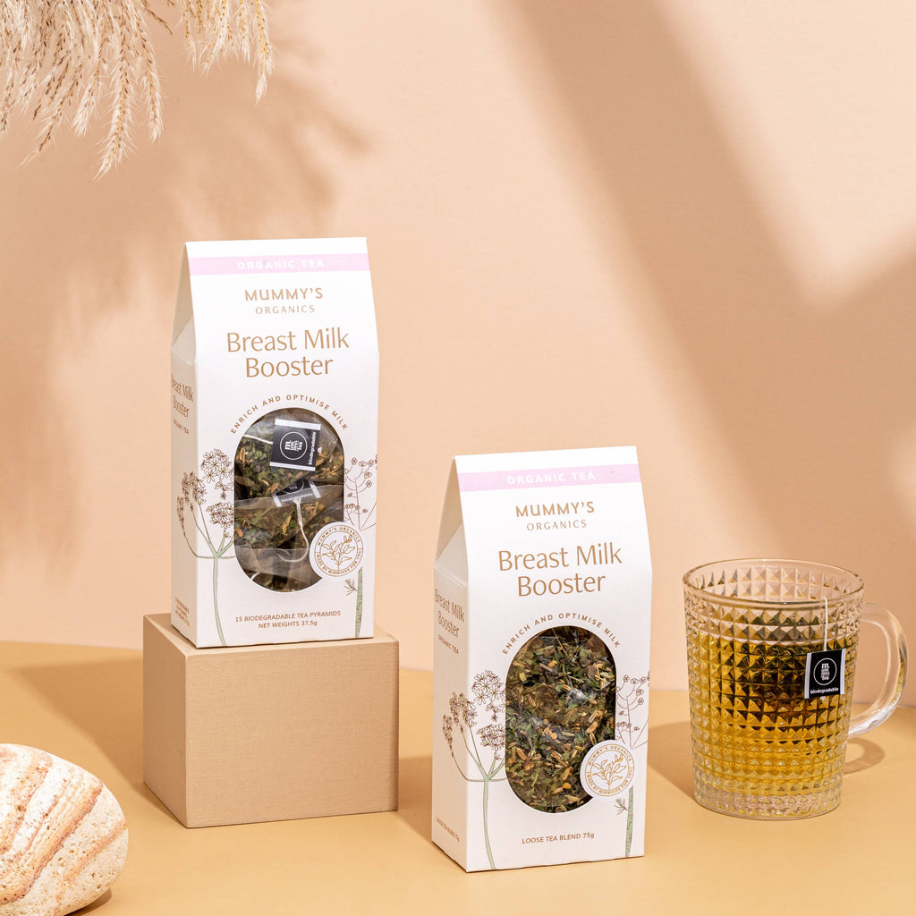 Two boxes of 'Mummy's' Breast Milk Booster on a beige background with a glass of tea.