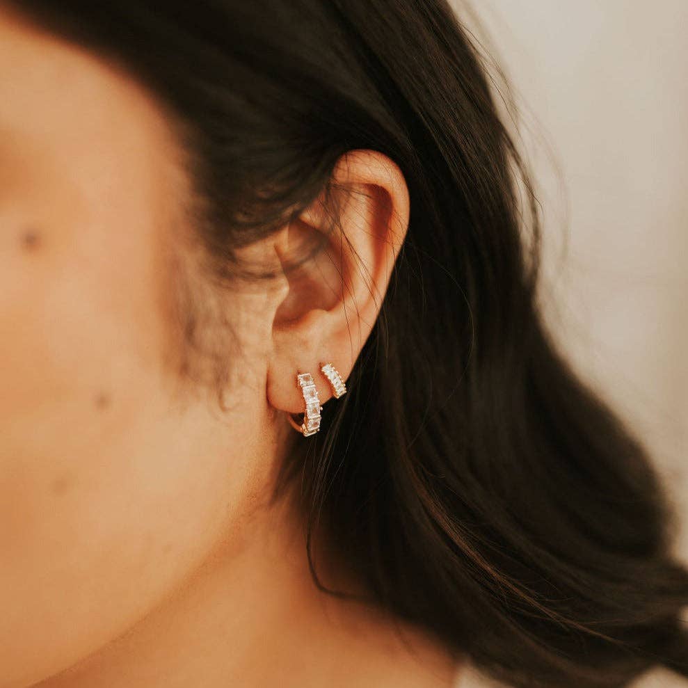 Close-up of a person wearing diamond hoop earrings with a blurred background