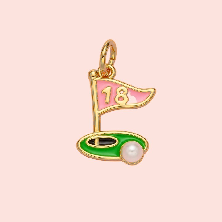 Gold pendant shaped like a golf flag with a pink top and green base on a light pink background