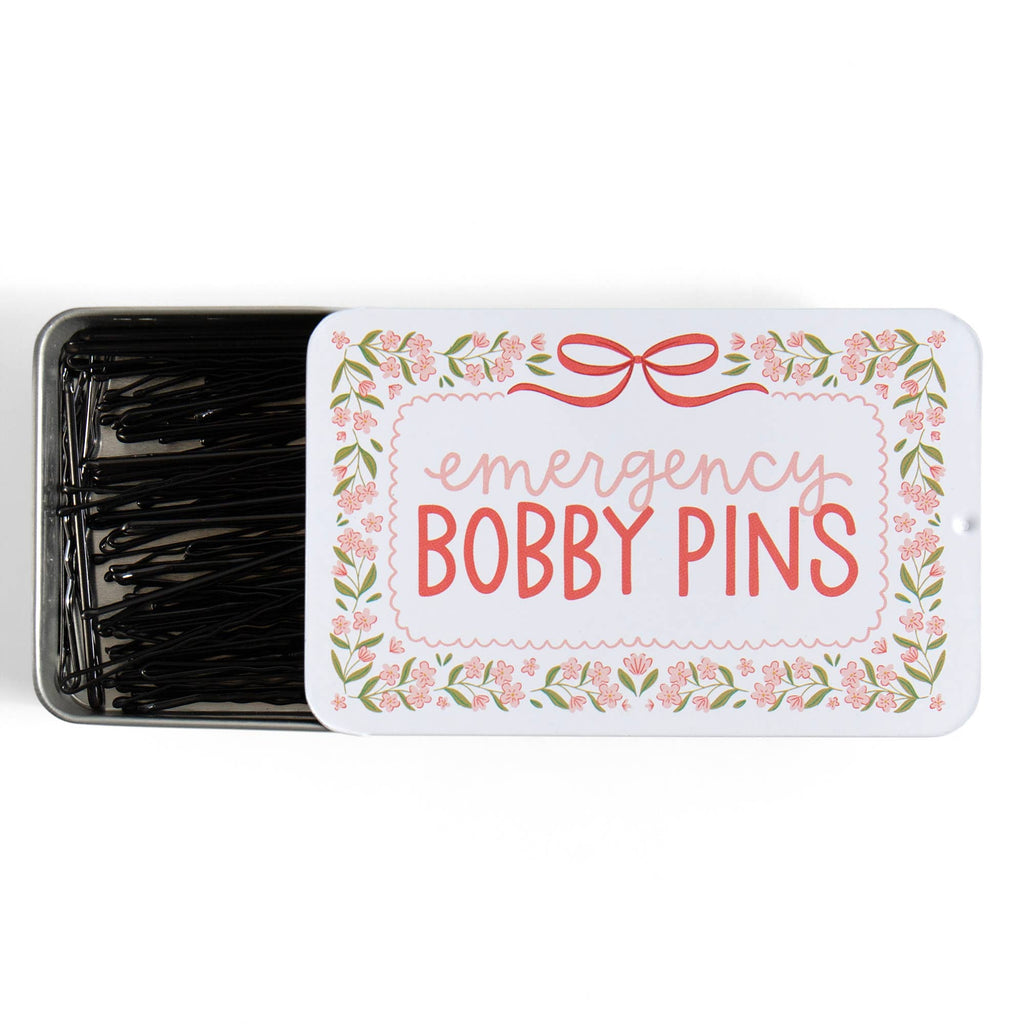 Tin of emergency bobby pins with decorative label on a white background