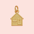 Gold house-shaped pendant on a pink background