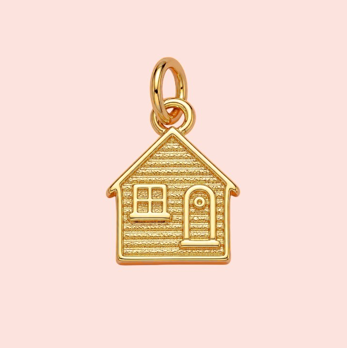 Gold house-shaped pendant on a pink background