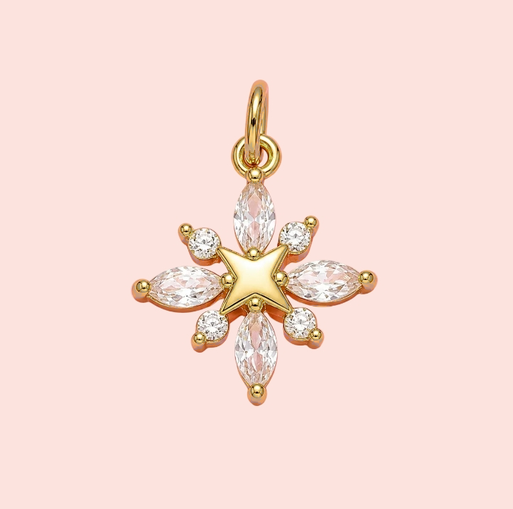 Gold star-shaped pendant with clear stones on a pink background