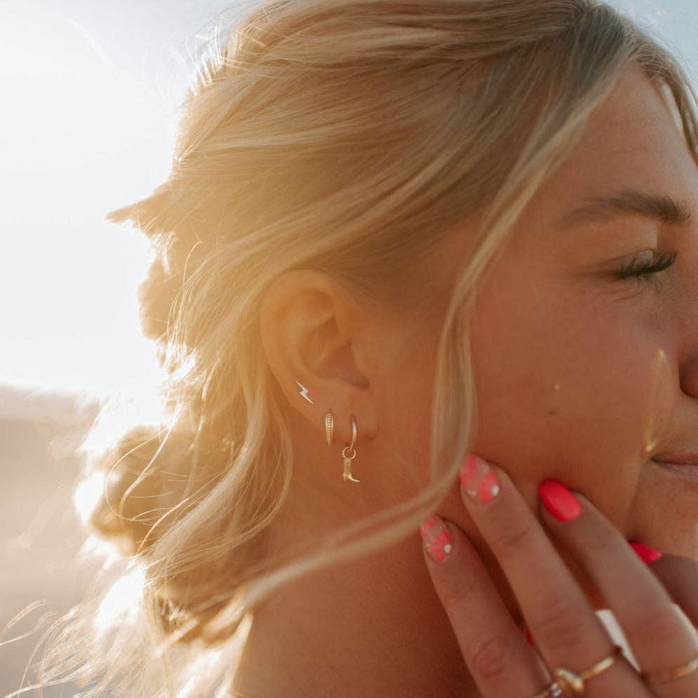 Close-up of a woman wearing gold hoop earrings with a blurred background