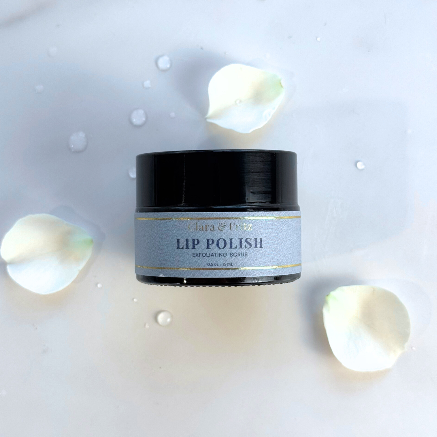 Jar of Clara & Co. Lip Polish on a light gray background with lip balm pieces.